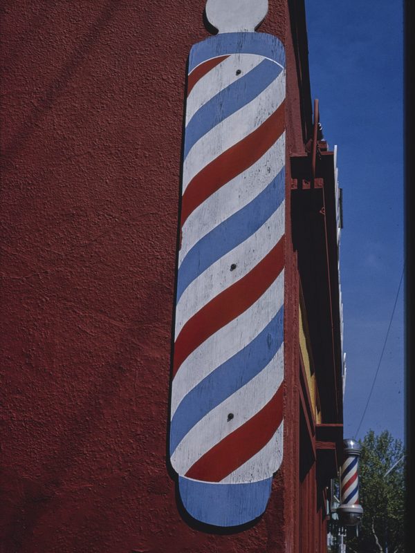 A striped barber pole mounted beside a shop door