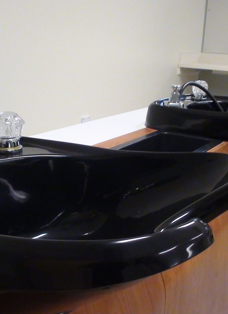A black backwash basin set into a wooden plinth, seen close up.