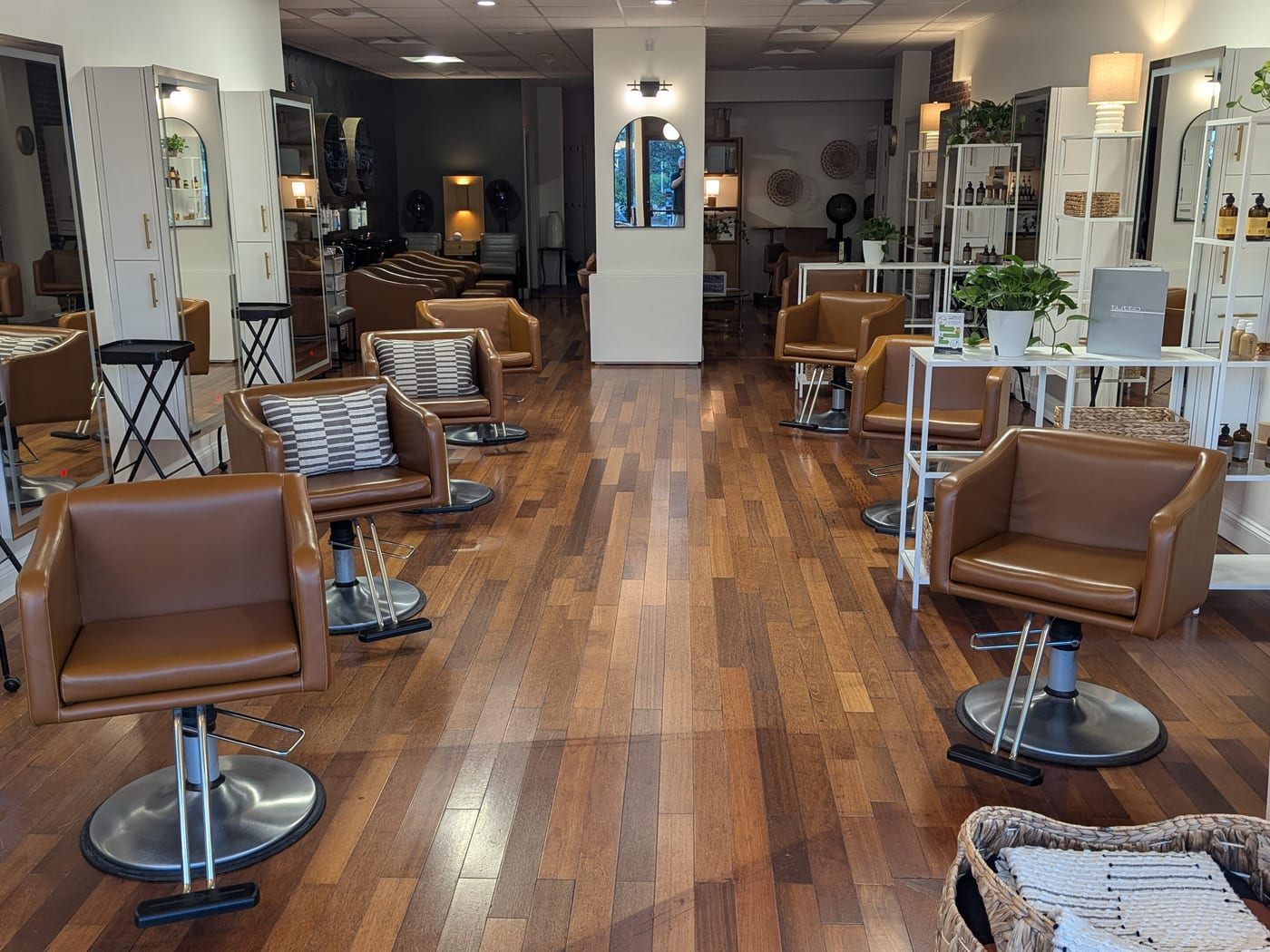 Styling chairs and mirrors along a salon floor, with product shelves at the back.