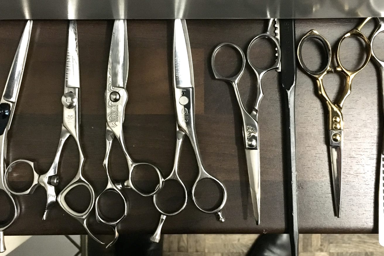 Several pairs of professional haircutting scissors of different lengths laid out side by side.