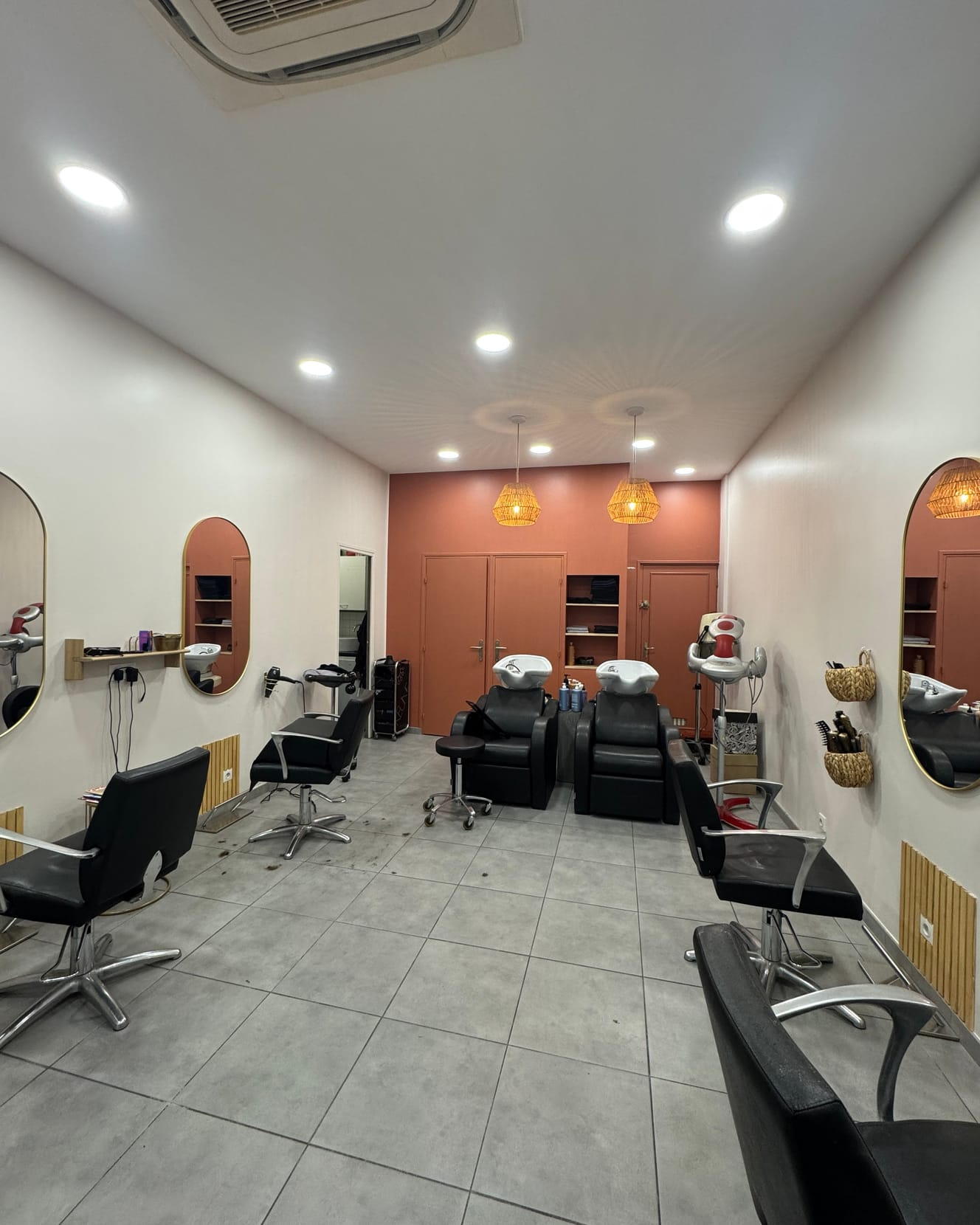 A salon workstation with a mirror, a chair and styling tools laid out on the counter.