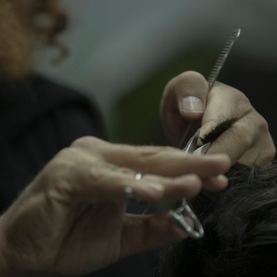 Hands holding shears and a fine comb close over dark hair
