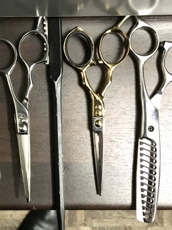 Cutting and thinning shears hanging in a row on a rail
