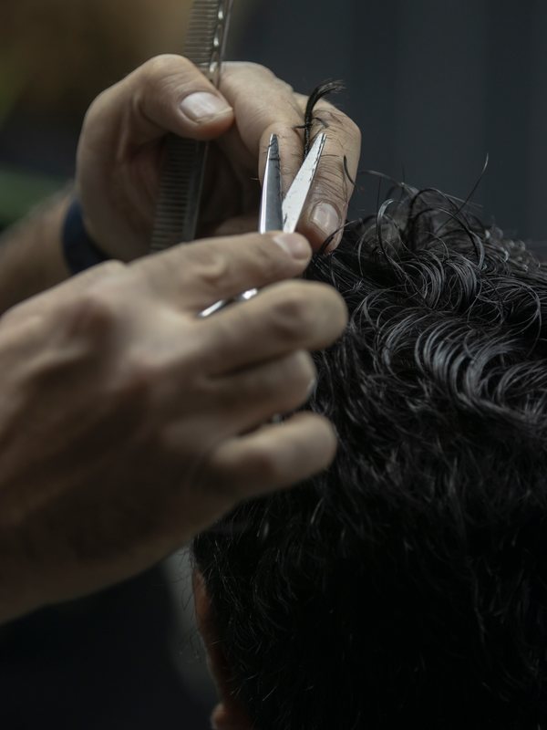 Shears and a comb working through a head of dark curls