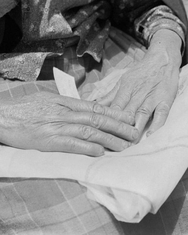 A close black and white study of a pair of hands holding a piece of cloth.