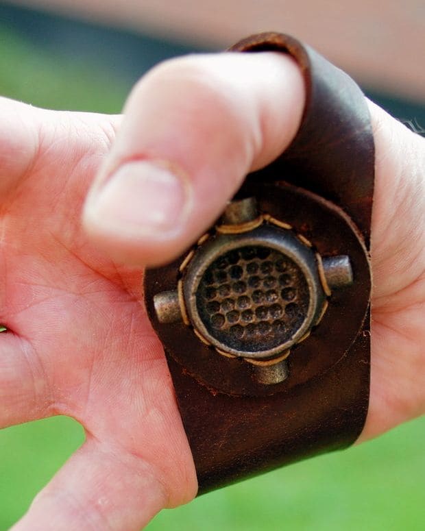 A hand wearing a leather sailmaker's palm, used to push a heavy needle through cloth.