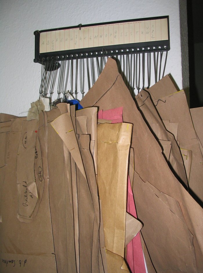 Paper patterns cut and labelled by hand, hung on a rack