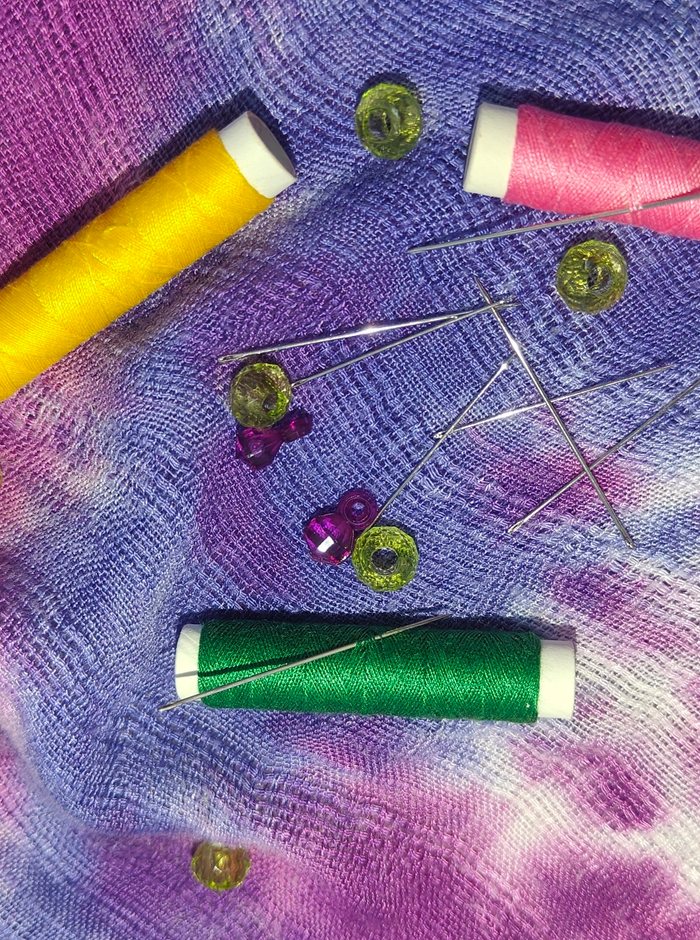 Needles threaded and set alongside loose beads