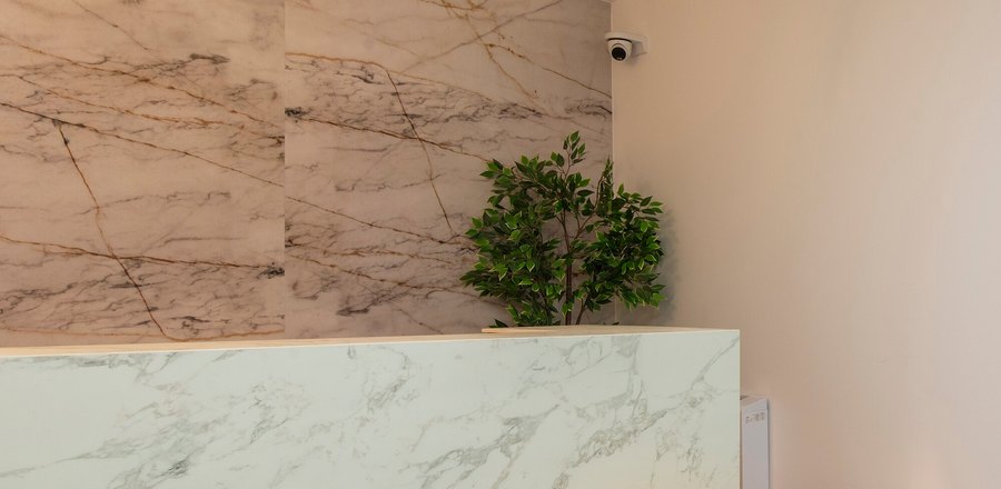 Marble reception counter below a veined stone wall, lit from beneath