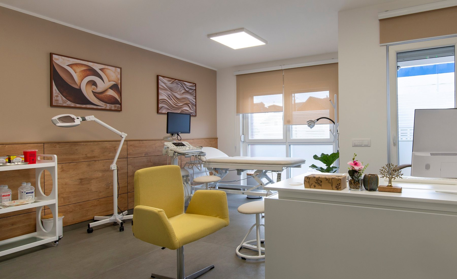 A bright treatment room with a couch, magnifying lamp and consultation chair