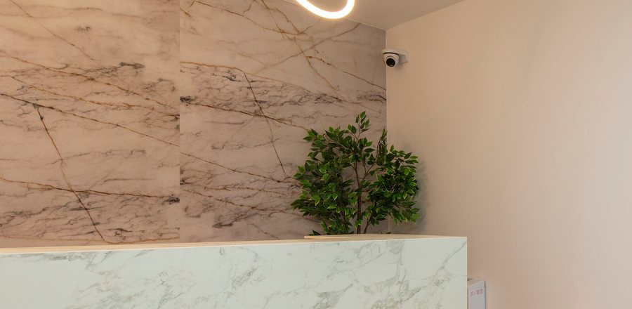 Marble reception desk beneath a brass pendant light