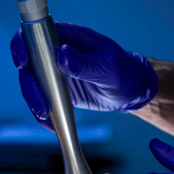 Gloved hands guiding a fractional laser handpiece