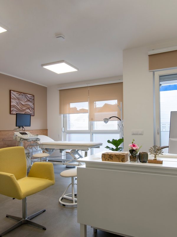 Bright treatment room with a magnifying lamp and a treatment couch