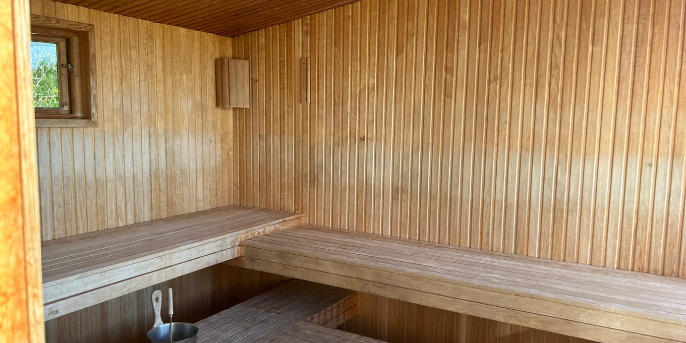 A cedar sauna interior with a slatted bench along the wall.