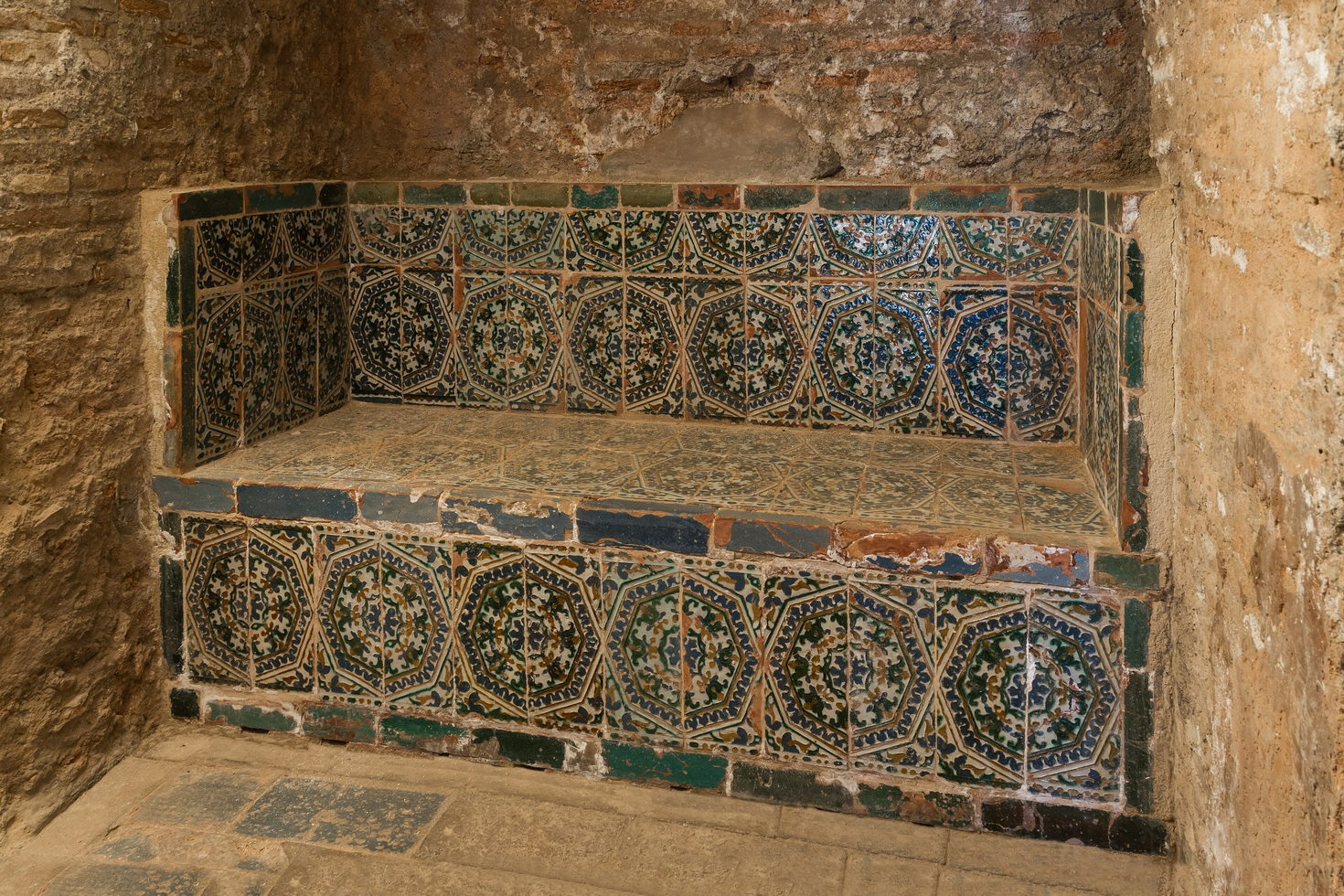 A stone bench in a vaulted historic bathhouse, lit by daylight from above.