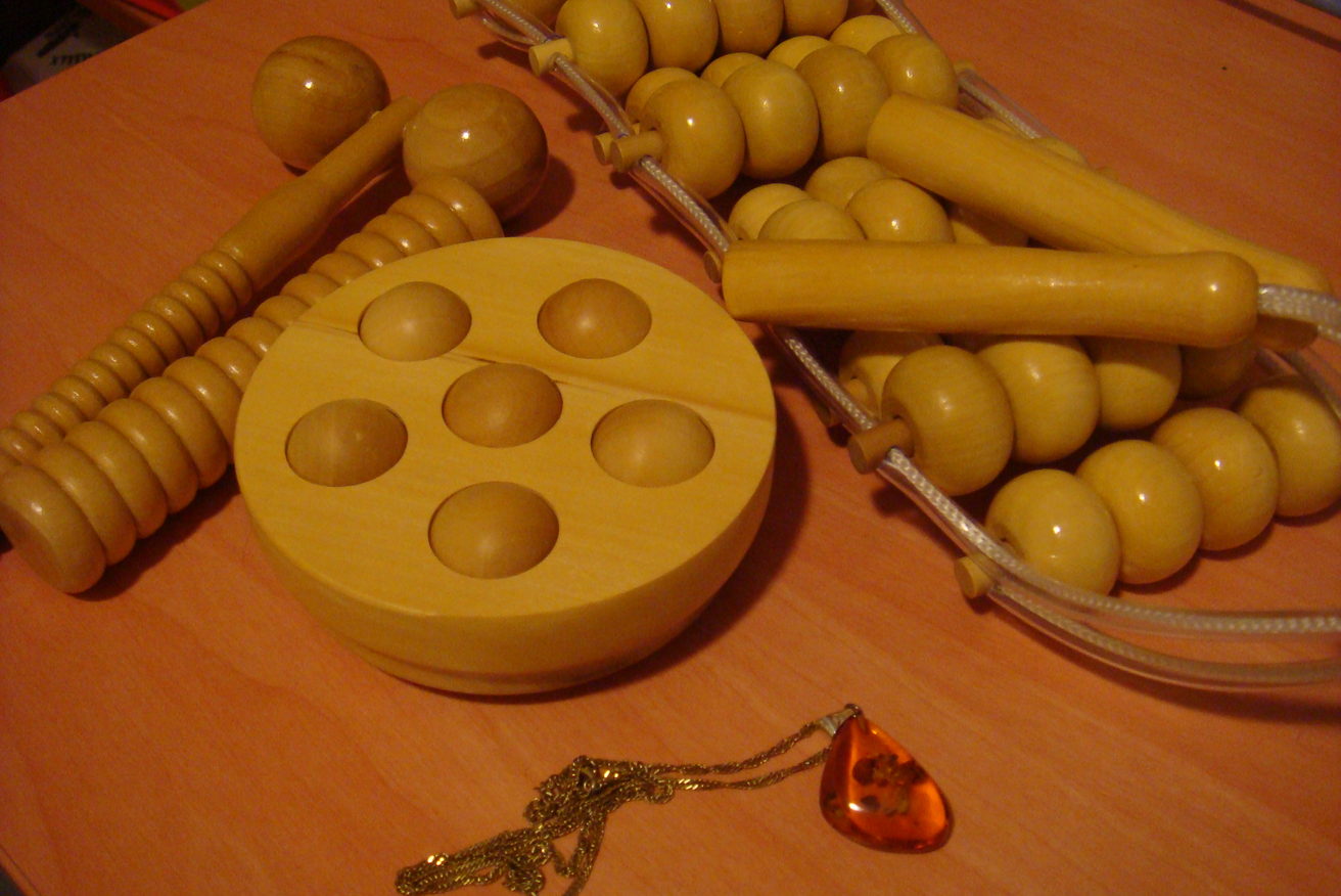 Wooden massage rollers and a hand-held tool laid out on a table.