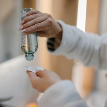 Hands pouring solution from a bottle onto a gauze pad
