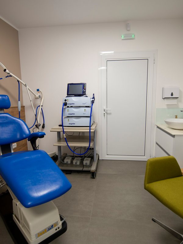 A treatment room with a blue reclining chair and medical equipment