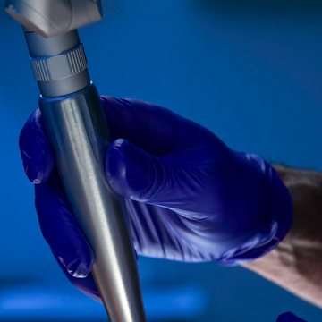 A gloved hand holding a laser resurfacing handpiece
