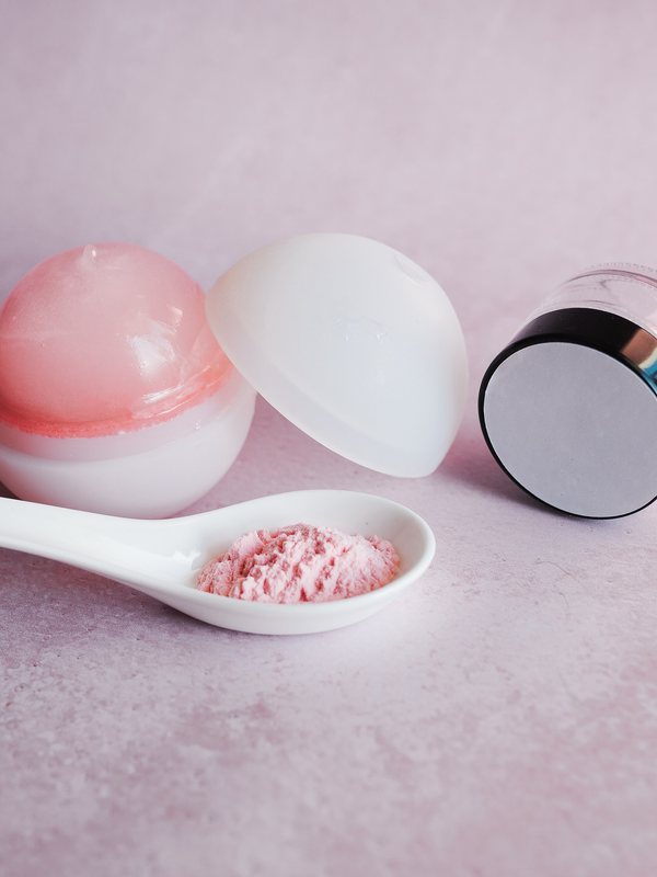 Skincare bottles and jars on a soft pink background