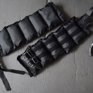 A pair of adjustable ankle weights on a gym floor
