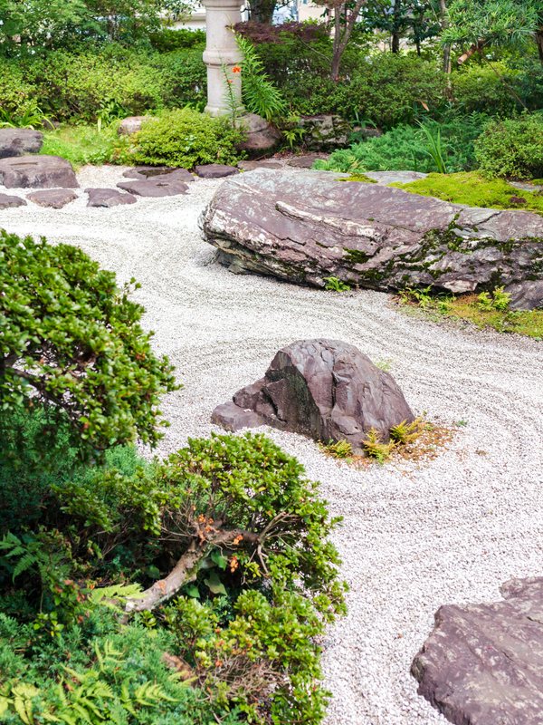 A dry garden of raked gravel, weathered boulders and clipped shrubs
