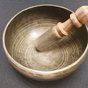 A singing bowl being played with a wooden mallet
