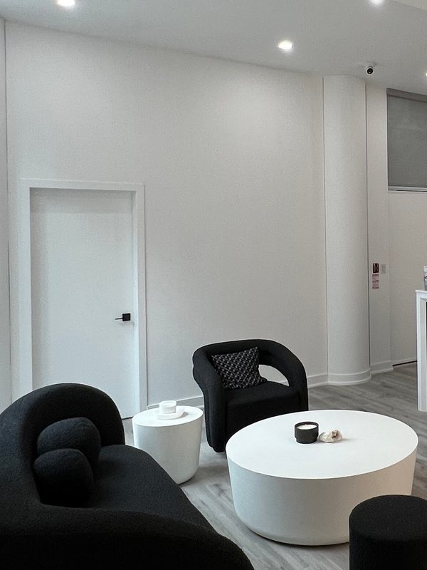 Black tub chairs and round white tables in a bright waiting area