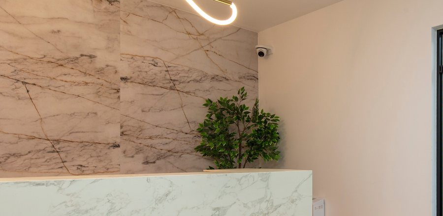 Marble reception wall and desk under a curved pendant at the clinic entrance