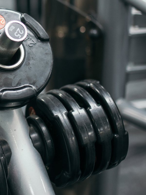 Heavy rubber-hex dumbbells racked in matched pairs on the Atlas strength floor