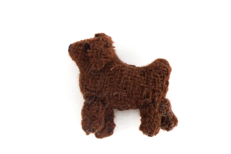A knitted toy dog standing on a plain white background.