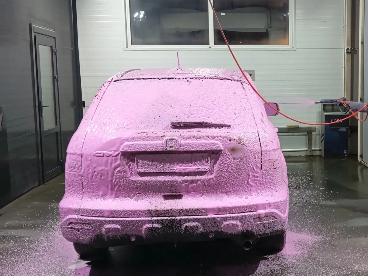 Vehicle covered in pre-wash foam inside the wash bay