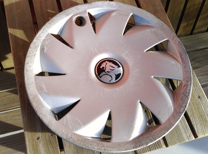 A wheel trim off the car and cleaned, laid on a workbench