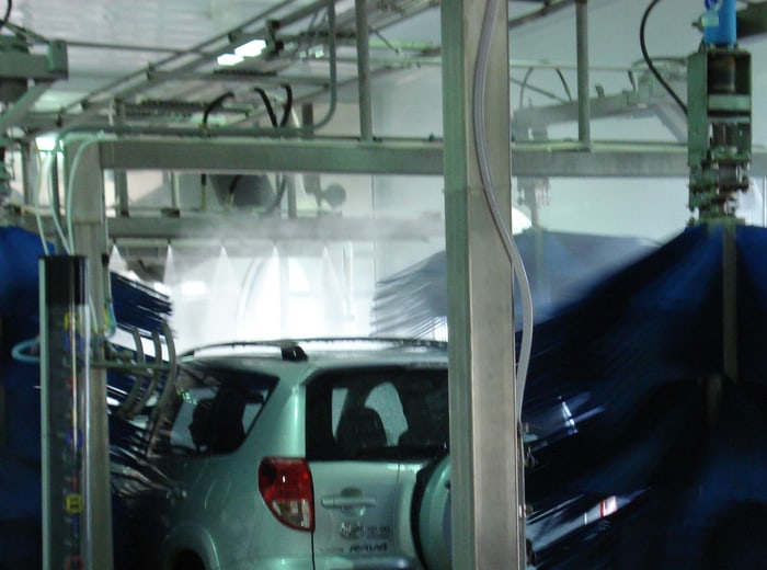 A car on the track between the dark side brushes of an automatic bay