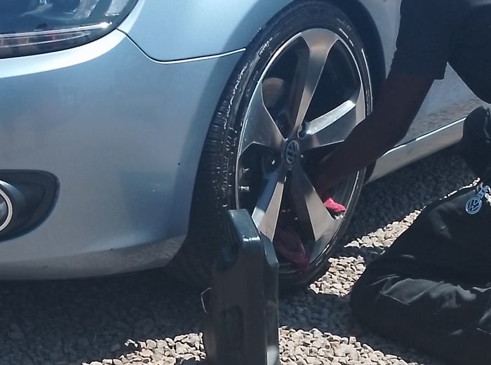 Hands working a cleaner into an alloy wheel and tyre