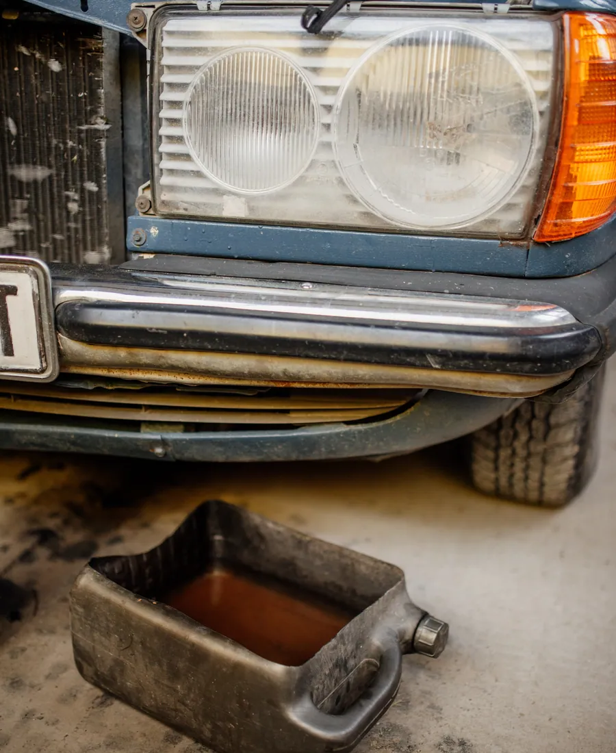Close crop of a drain pan set beneath a car during an oil change