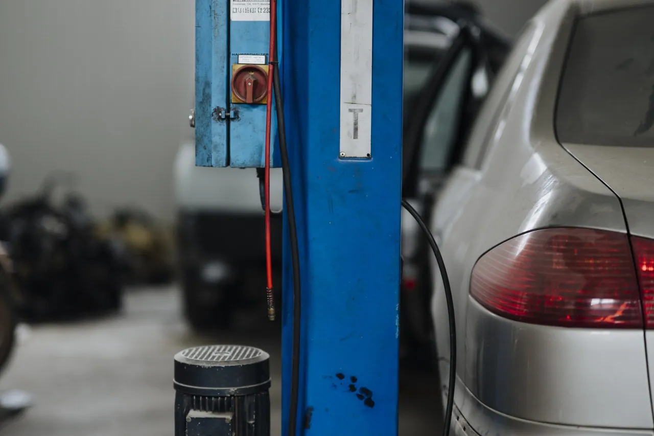 Vehicle beside a two-post lift in a clean repair workshop