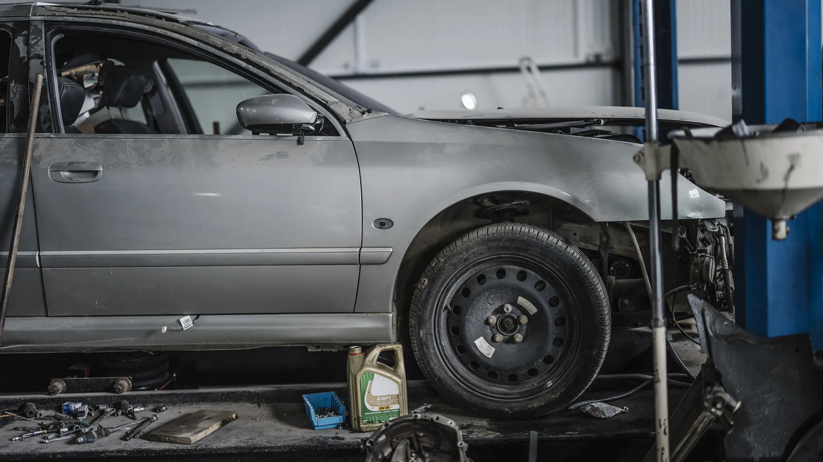 Auto shop bay with a vehicle raised on a lift and tools laid out on the floor