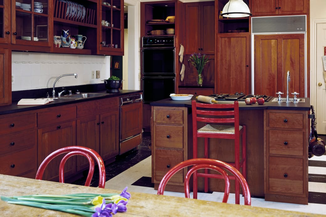 A fitted kitchen with cherry cabinets, a double wall oven and an island with a gas hob.