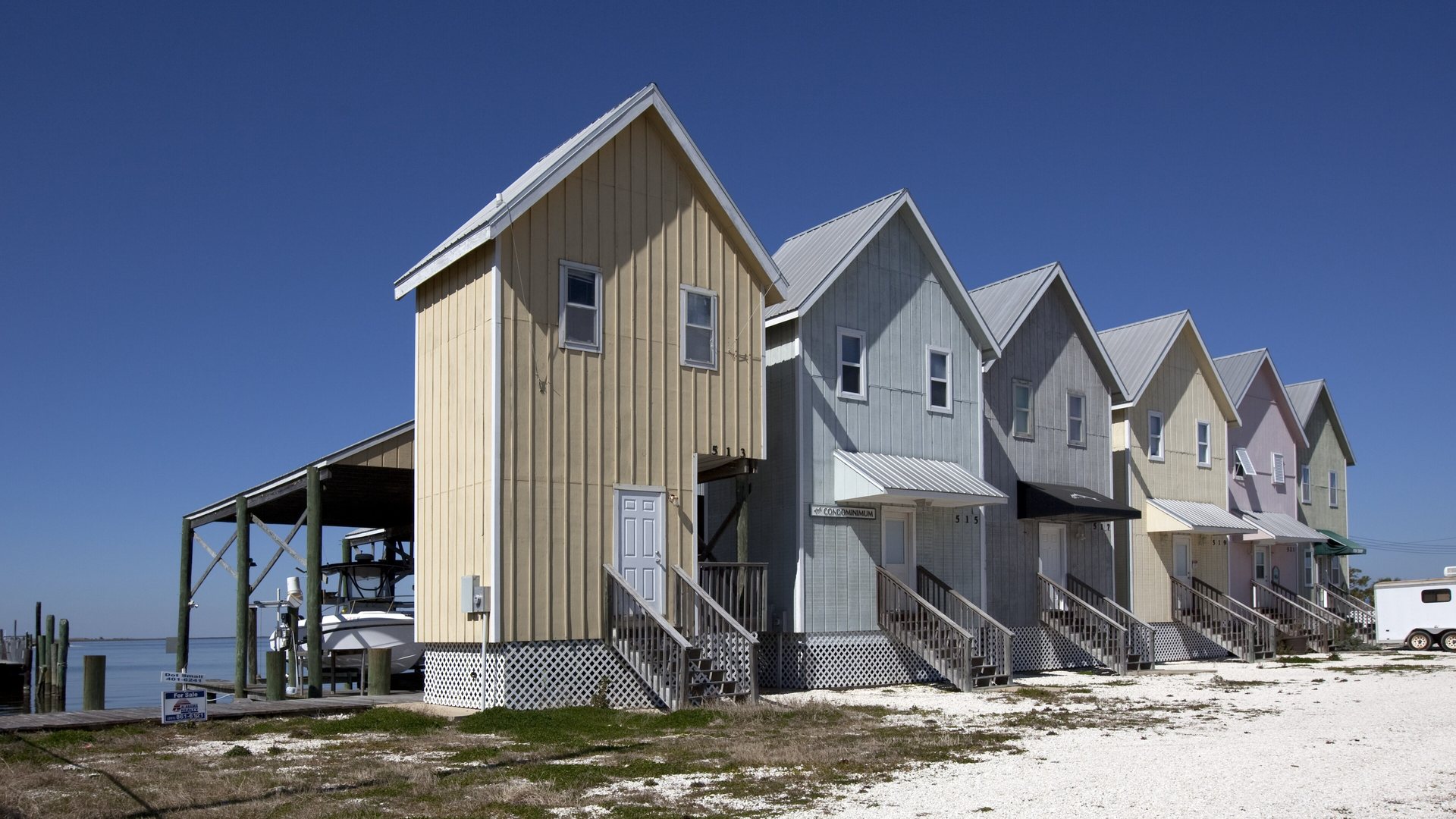 Beach houses lined up along the shoreline under a clear sky