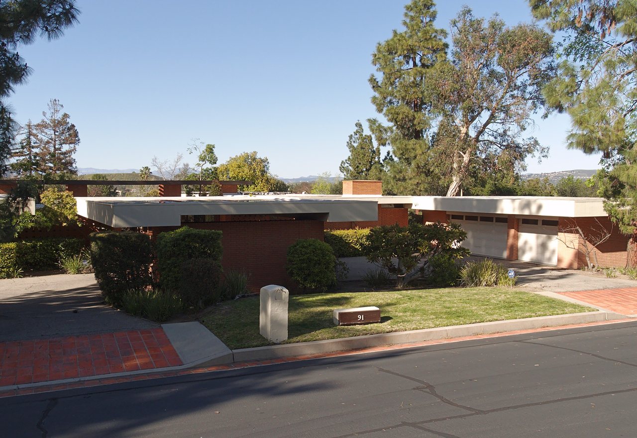 Hillside Eco-Modern — a low mid-century modern house with a flat roof set among tall trees, Fernvale, OR