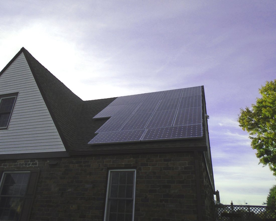 A steep roof covered with dark solar panels against an evening sky