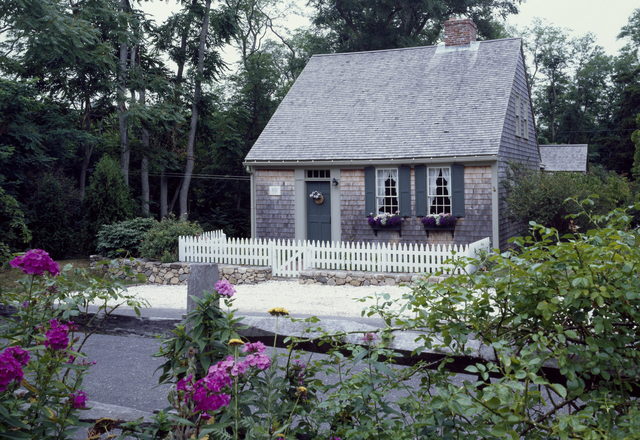 Riverside Cape Cottage — shingled Cape Cod cottage behind a rose-covered fence