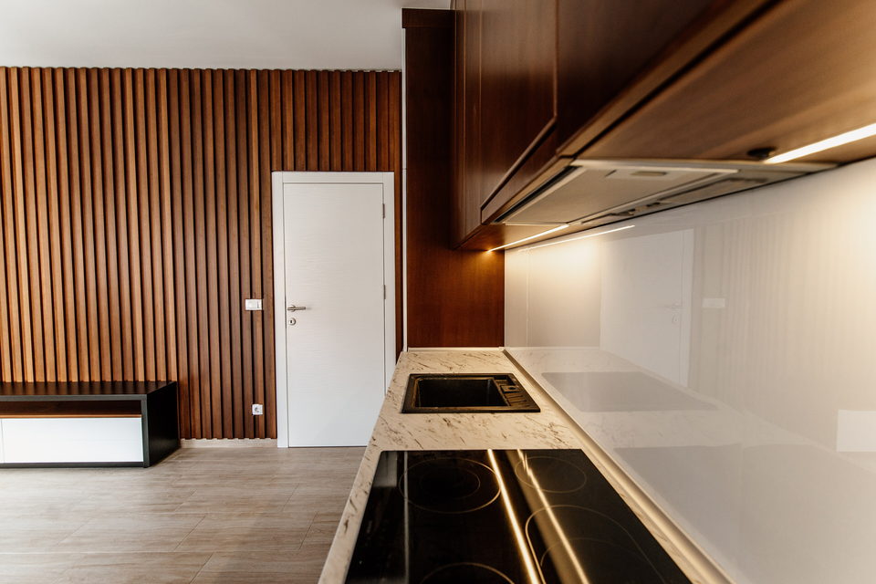Marble kitchen counters and walnut cabinetry against a slatted timber wall