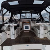 The wheel cockpit of a sailing yacht under a dark bimini.