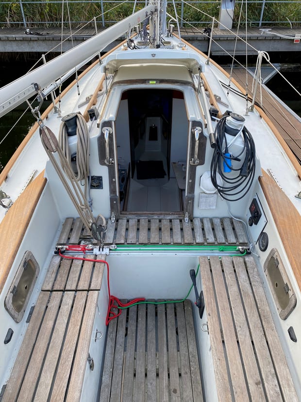A cockpit with teak seating, winches and coiled lines.