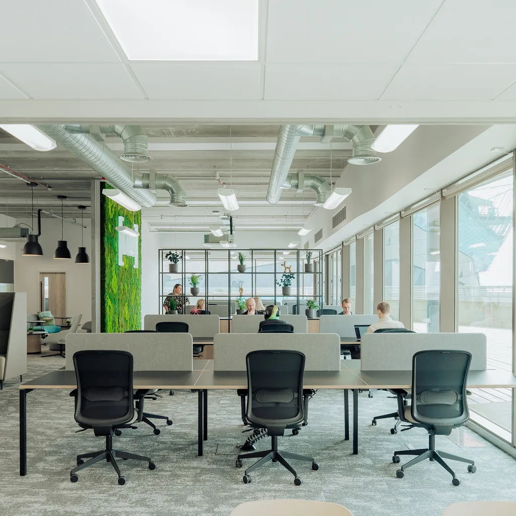 Desk pods and low screens define focus and shared-use areas.