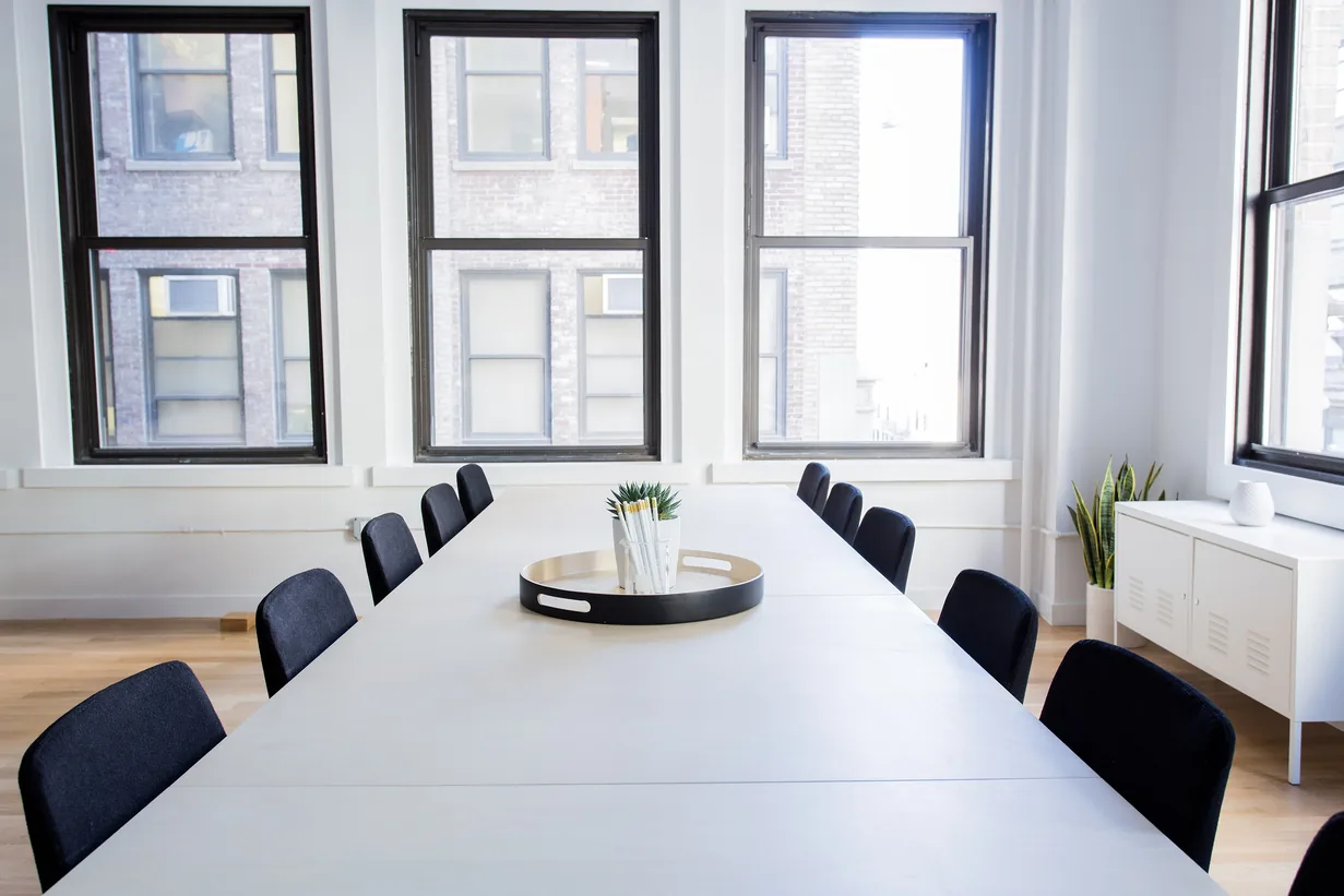 Bright meeting room with a long table and daylight through tall windows