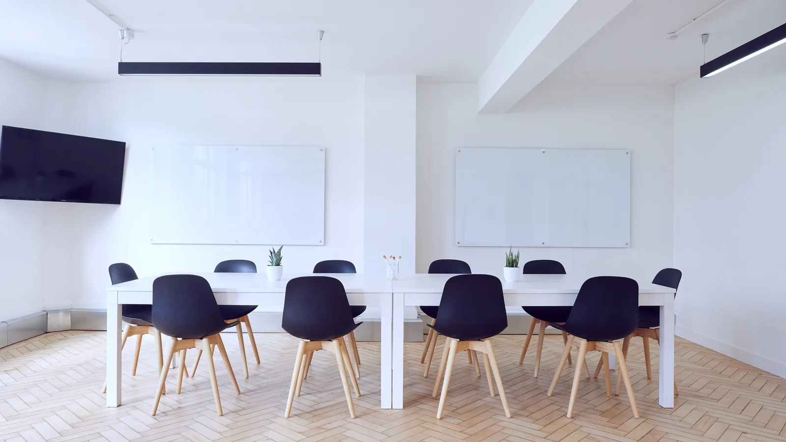 Bright workshop room with a long table, chairs and whiteboards