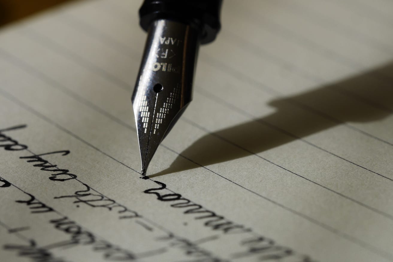A hand writing in a notebook with a fountain pen.